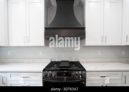 remodeled kitchen has white cabinets installed and modern appliances Stock Photo
