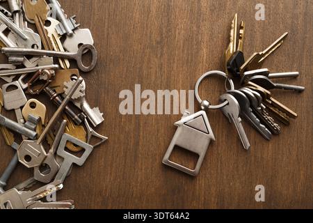 Collection of Various Keys Placed on a Wooden Table With a Keyring Showing a House Shape Stock Photo