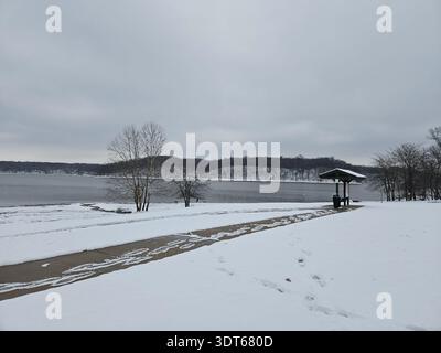EDITORIAL USE ONLY- ​AMELIA, OHIO - December 2025: A quiet, snow-covered landscape at East Fork State Park near Amelia, Ohio. The image captures the deserted beach and a picnic shelter overlooking the frozen banks of William H. Harsha Lake under a heavy, overcast winter sky. Stock Photo
