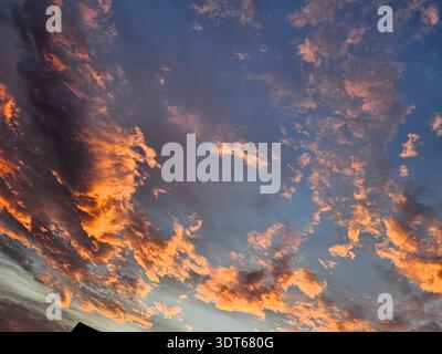 EDITORIAL USE ONLY- AMELIA OHIO JULY 2025:  ​Vibrant sunset over Amelia, Ohio, in July 2025, featuring dramatic altocumulus clouds illuminated with orange and gold light against a deep blue summer sky. Stock Photo