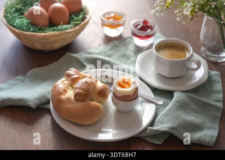 Breakfast with boiled egg, bun, coffee and jam on a table with brown Easter eggs in a basket  holiday morning, selected focus Stock Photo