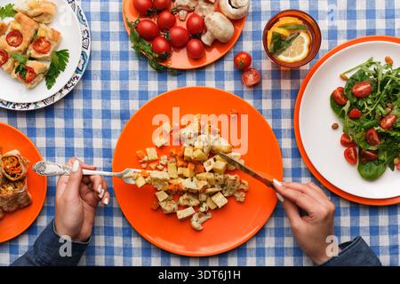 Family Meal on a Blue Checkered Tablecloth With Various Dishes Served on Colorful Plates Stock Photo