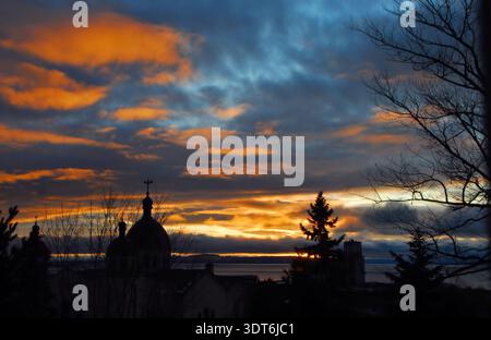 Colorful sunrise on Lake Superior in Thunder Bay, Ontario. Canada. Foreground has some trees and the domes of a Ukrainian Catholic Church. Stock Photo