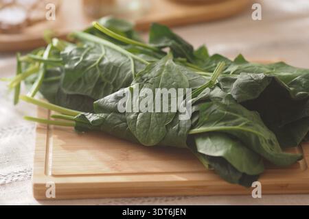 Fresh spinach leaves on a wooden cutting board in a kitchen Stock Photo