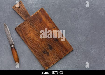 Wooden Cutting Board With Knife Resting Beside It on Gray Surface Stock Photo