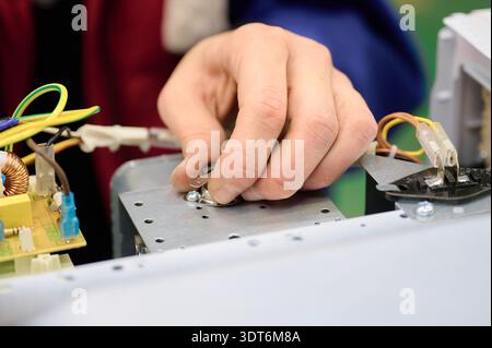 Assembly process of microwave oven electrical components on conveyor system in manufacturing facility Stock Photo