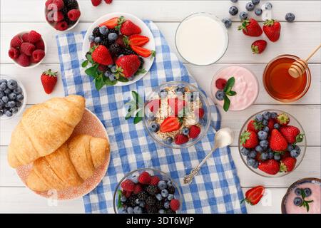 Morning Breakfast Spread With Fruits, Yogurt, Croissants, and Honey on a Blue Checkered Tablecloth Stock Photo