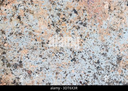 Rough multicolored textured background resembling weathered concrete, featuring scattered dark speckles, earthy stains, blue-gray tones, and irregular Stock Photo