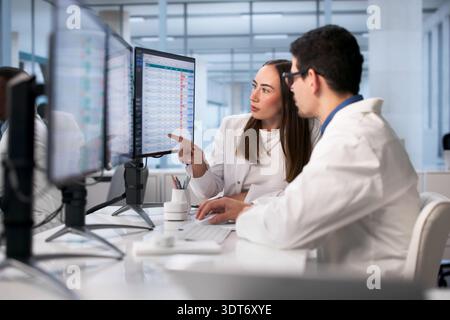 Group Of Diverse Clinicians Analyzing Medical Data Using Computers In Hospital. Stock Photo