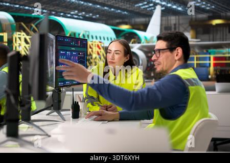 Engineers Utilizing CAD Models On Computer In Aerospace Manufacturing Facility. Stock Photo