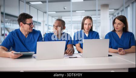 Medical Professionals Collaborate In Hospital Meeting Room, Discussing Patient Records. Stock Photo