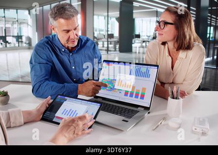 Financial Analysts Discussing Performance Indicators At Multicultural Company Meeting With Laptops. Stock Photo