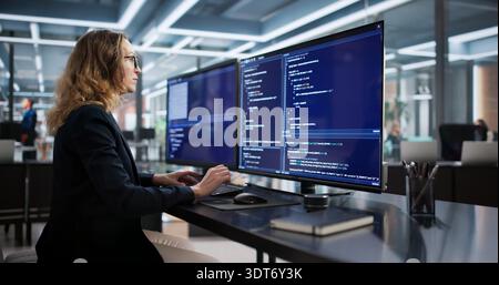 Female Programmer Developing Secure Software From Office Desk Using Computer Stock Photo