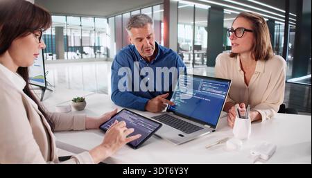Business Team Meeting To Develop Software Code On Laptop And Tablets. Stock Photo
