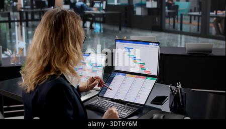 Woman Using Kanban Software To Manage Project Schedule On Laptop. Mature Woman Updating Digital Calendar Stock Photo
