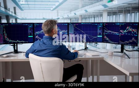 Senior Broker Analyzing Stock Market Data On Multiple Computer Screens Stock Photo