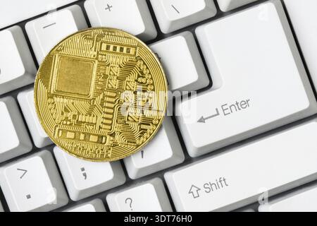 Gold bitcoin coin, reverse side lying on white computer keyboard Stock Photo
