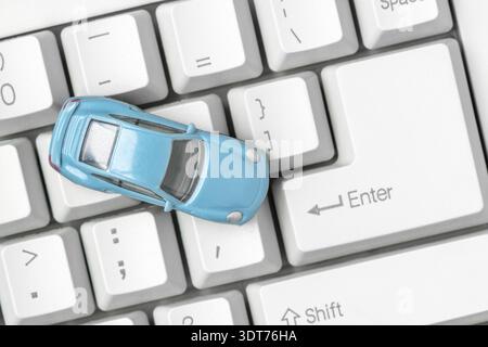 Small blue car on the computer keyboard. Car business concept such as transportation, rental, sell and buy Stock Photo