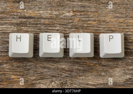 Four computer keyboard keys arranged to spell HELP word on the wooden background Stock Photo