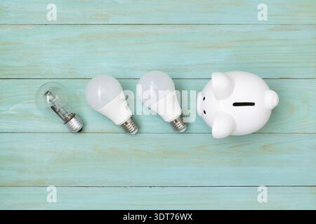 Piggy bank and light bulbs on blue wooden background. Energy saving Stock Photo