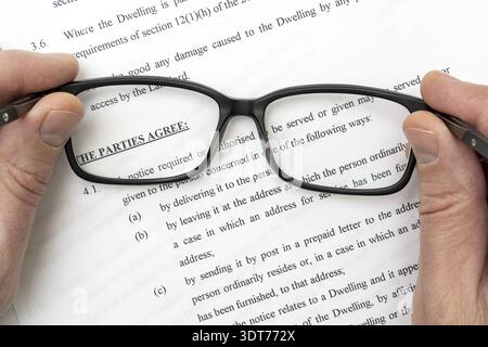 Studying lease agreement. Copy of a lease agreement behind glasses on a desk Stock Photo
