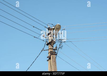 Electric wires hanging on a pole with a lighting lamp Stock Photo - Alamy