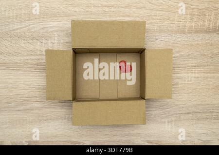 Small red heart on the bottom of cardboard box. Heart In The Open Cardboard Box Stock Photo