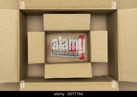 Shopping cart inside open rectangular cardboard box. Online internet shopping concept, e-commerce Stock Photo