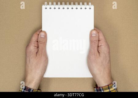 Hands holding a spiral notebook with blank sheets for writings. Flat lay top view Stock Photo