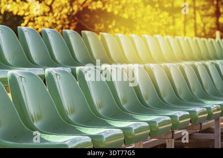 Rows of green plastic seats on the school stadium during fall season Stock Photo