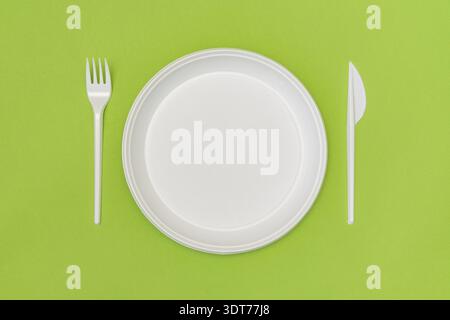 Set of white disposable tableware on the green background Stock Photo