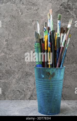 Dirty plastic flask with assorted painting brushes Stock Photo