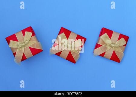Three Gift boxes with golden bows on blue background. Top view Stock Photo