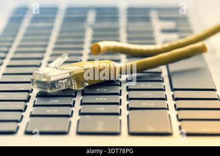 Laptop keyboard with cut internet cable. Concept of internet censorship and interruption Stock Photo