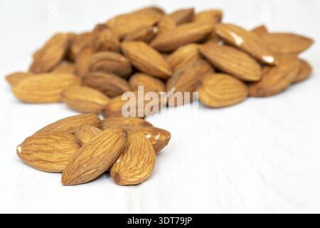 Pile of almonds seeds on white wooden background Stock Photo