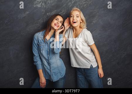 Two Friends Enjoy a Fun Moment Together in a Studio Setting With a Dark Background and Bright Smiles Stock Photo