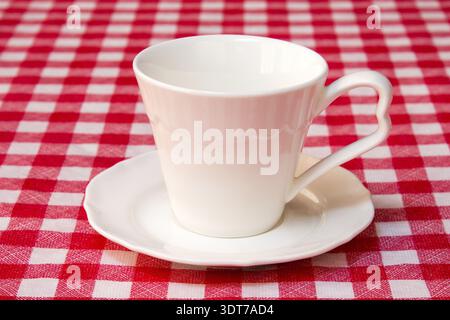 White cup on the checkered tablecloth texture Stock Photo