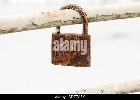 Old rusty padlock hanging on metal bar Stock Photo