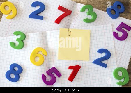 Squared exercise book with colored numbers and blank sticky note Stock Photo