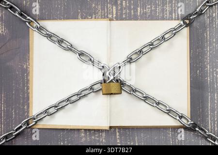 Open book with chain and padlock on wooden background Stock Photo