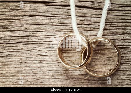 Wedding rings hanging on rope over wooden background. Vintage image Stock Photo