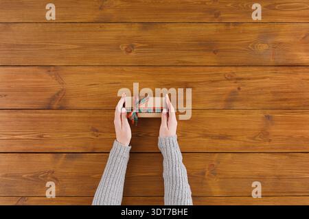 Holds a Small Gift Box With a Ribbon on a Wooden Table in a Cozy Room Setting During a Festive Time Stock Photo