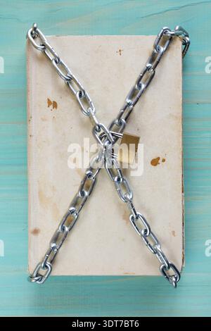Old book with chain and padlock on blue table Stock Photo