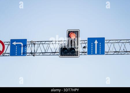 Close up of elevated traffic control signs on metal truss, featuring red stop signal, no U turn sign, and lane arrows for left and straight routes Stock Photo