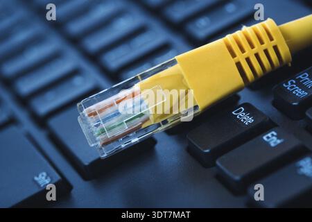 Yellow internet cable on computer keyboard with shallow depth of field Stock Photo