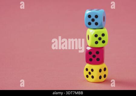 Stack of colorful dice on pink background. Copy space Stock Photo