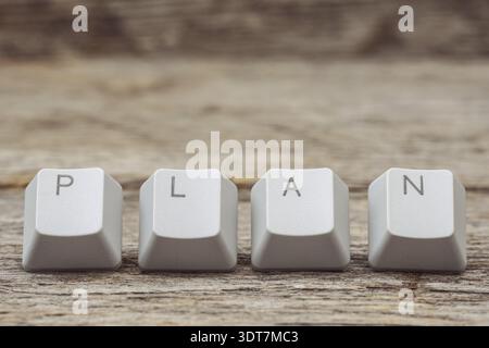 Computer keyboard keys arranged to spell PLAN word on the wooden background. Planning concept, business finance goal setting concept Stock Photo