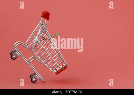Empty shopping cart on a red background. Grocery hand cart Stock Photo