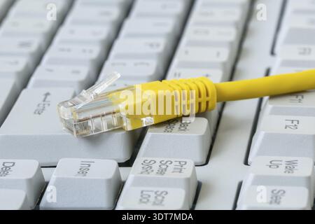 Yellow internet switch on old computer keyboard with big buttons. Internet cable, RJ-45 plug on computer keyboard Stock Photo