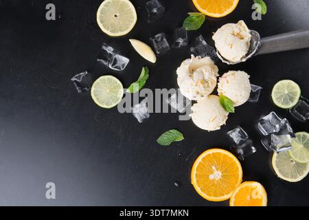 Melting Ice Cream With Citrus Fruits and Mint on a Black Surface at a Dessert Setting Stock Photo
